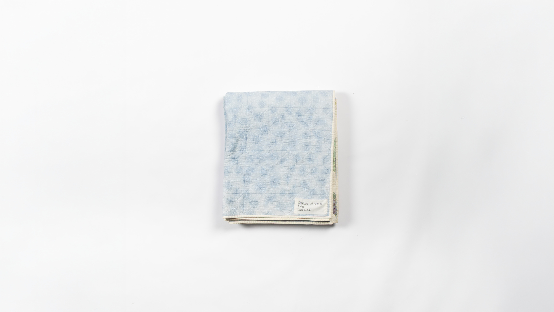 A folded quilt slowly unfolding to reveal its full pattern.