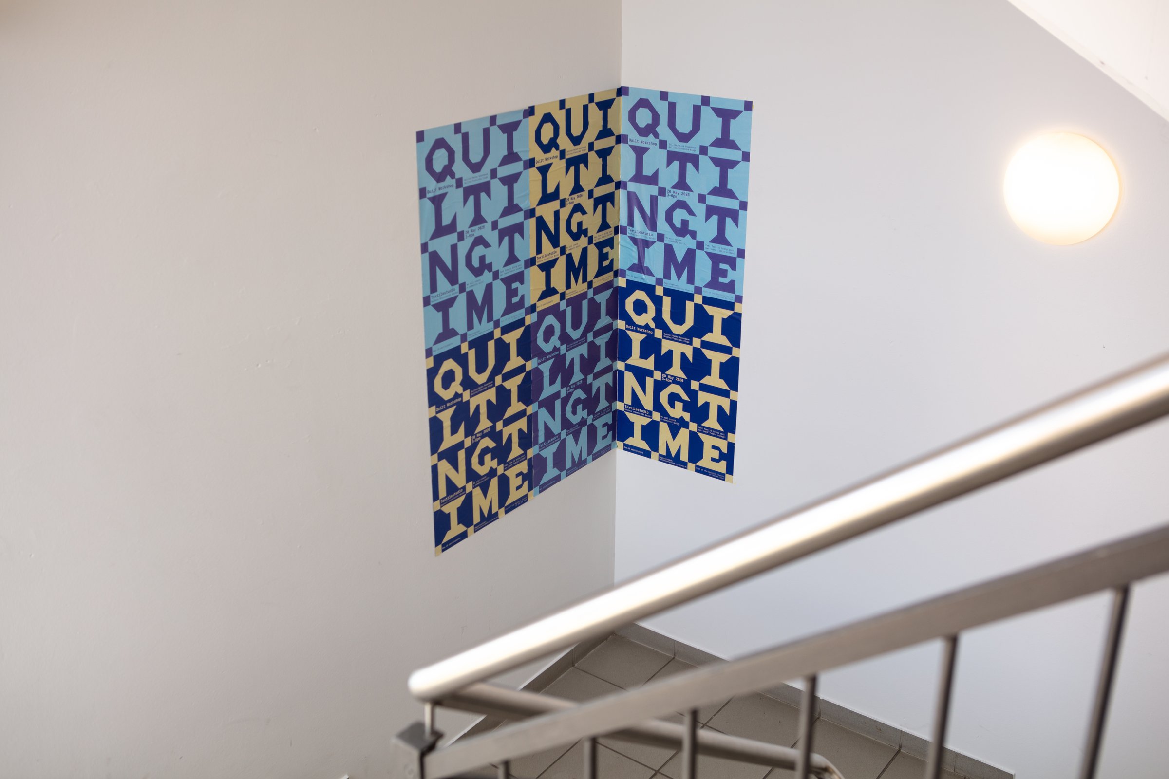 Several 'QUILTING TIME' workshop posters in blue, yellow and lilac patchwork blocks, pasted around a stairwell corner.