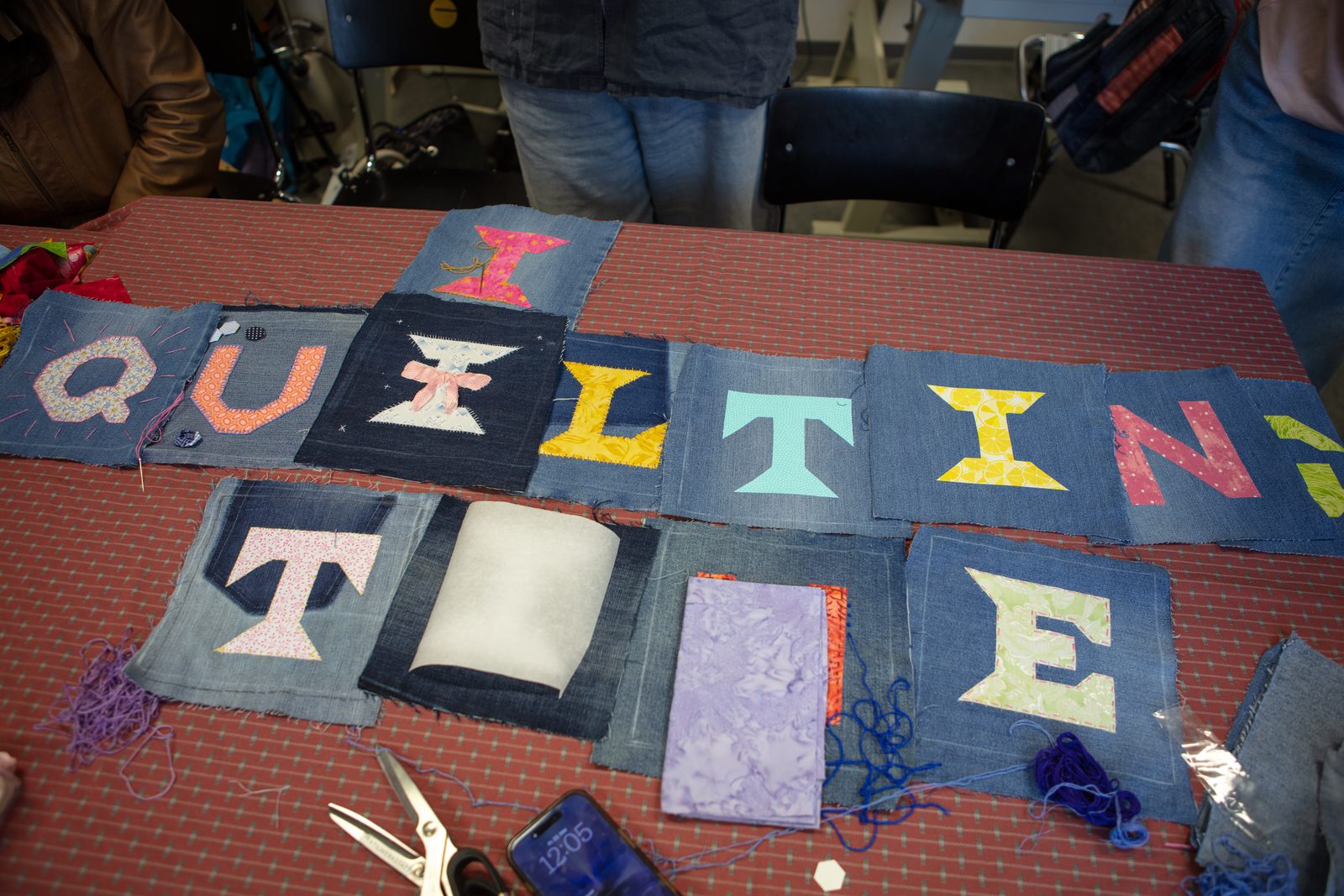 All the hand-sewn fabric letters laid out on a table, spelling QUILTING TIME.