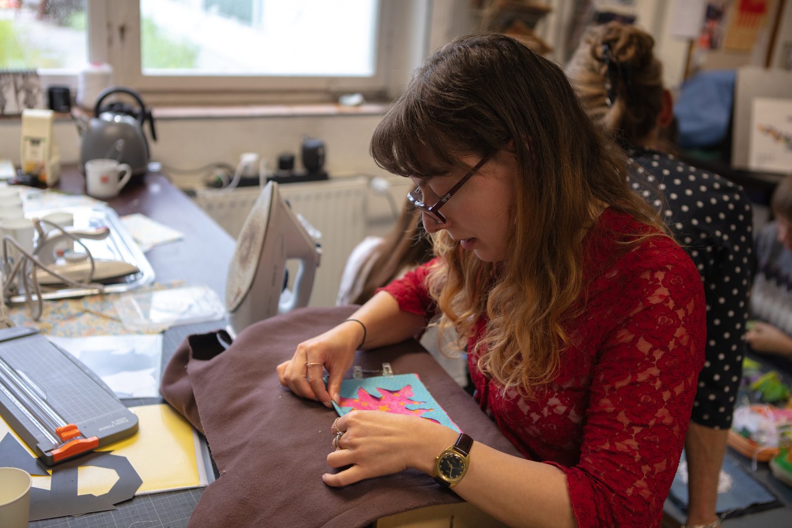 A quilter pressing a fabric seam flat at an ironing board.