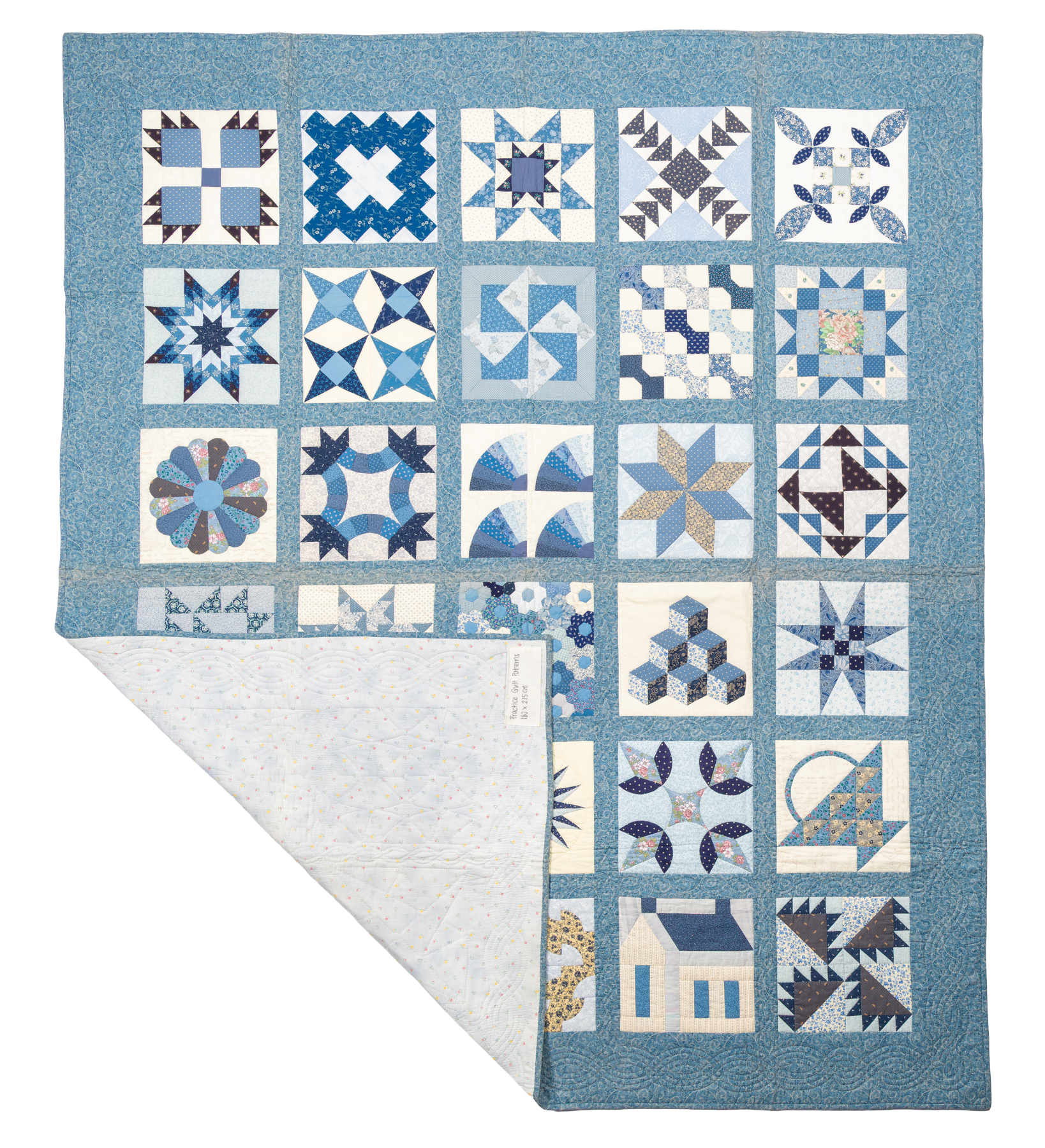 Practice Quilt, a blue sampler quilt of geometric blocks, photographed flat with its backing corner folded open.