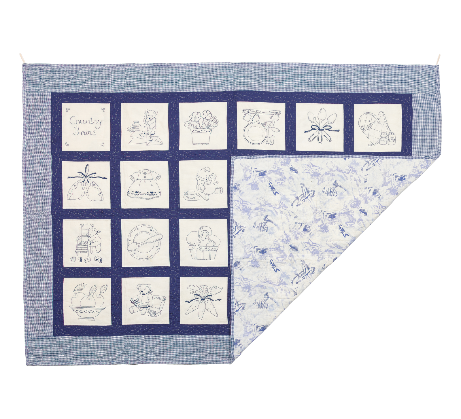 Country Bears, a quilt with kitchen-themed embroidered blocks on a blue gingham border, backing corner folded open to reveal a light blue floral print.