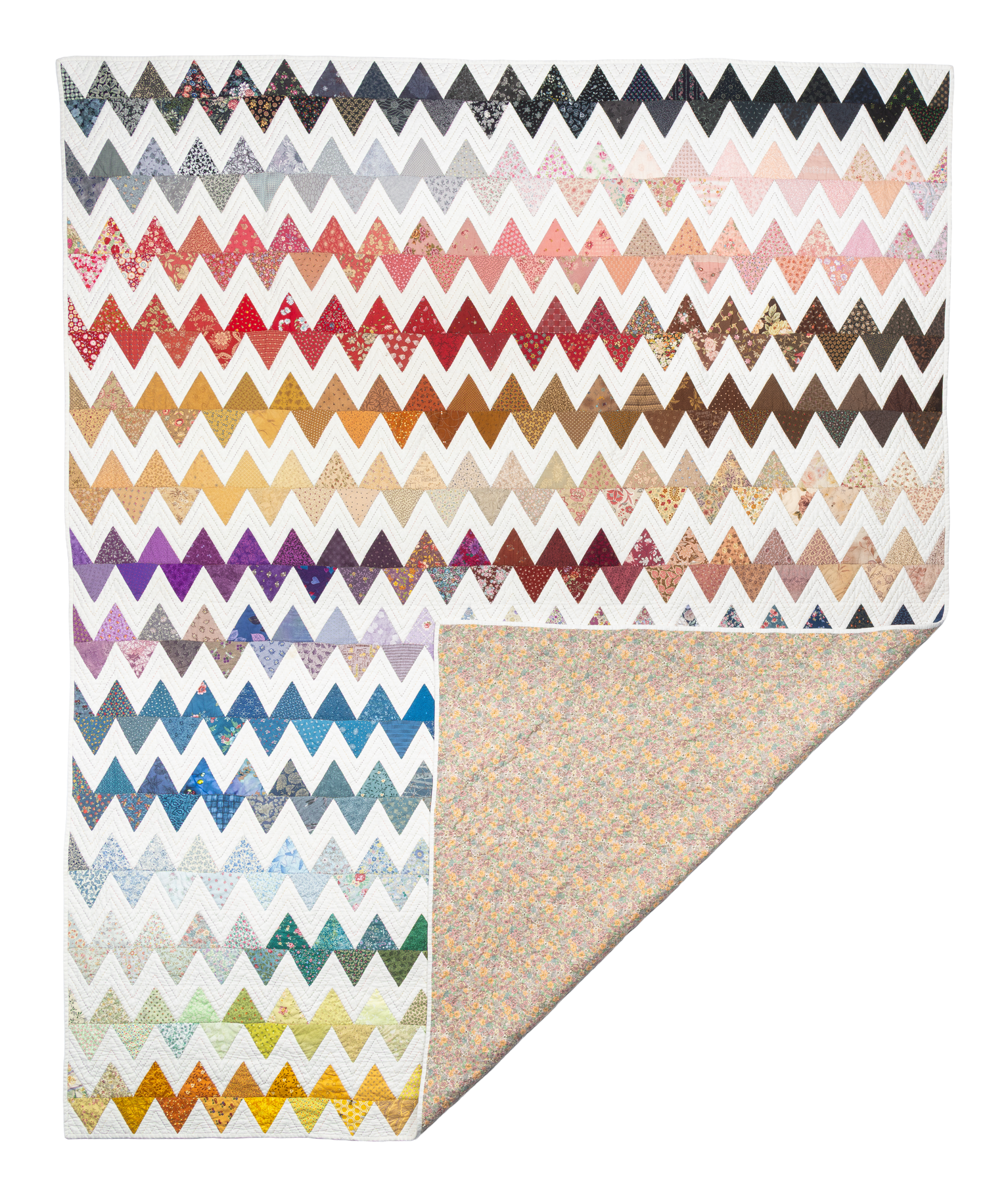 Zigzag Triangle, a quilt of colorful chevron rows in scrap fabric, with a floral backing corner folded open.