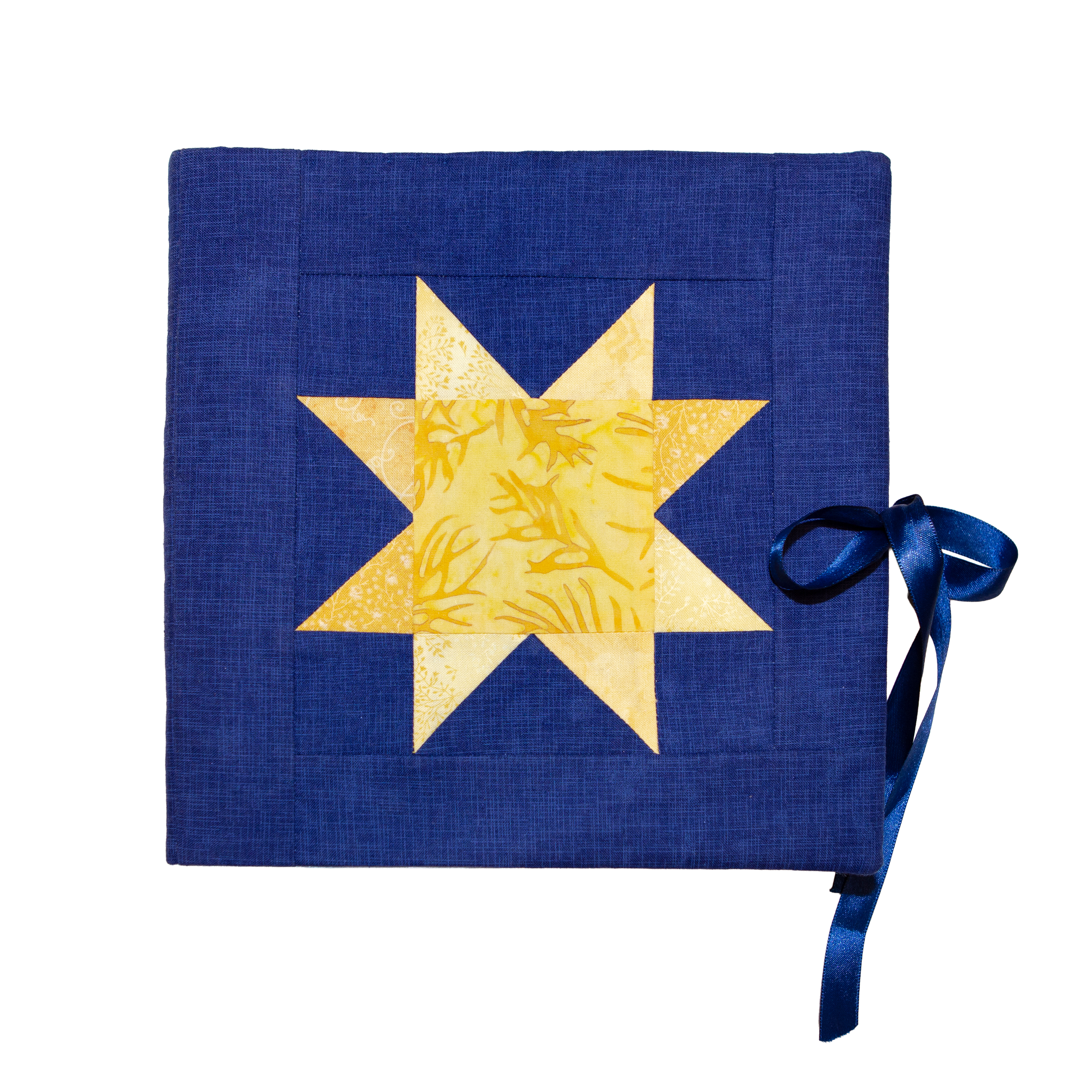 The fabric-bound cover of the printed Quilting Time book, dark blue linen with an appliqued yellow star quilt block and a satin ribbon tie.