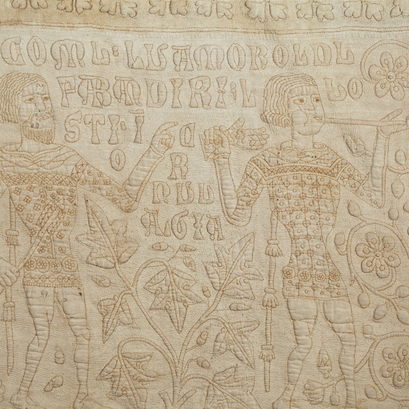 The Tristan Quilt with stitched figures and narrative embroidery, cropped in on the two embroidered men.
